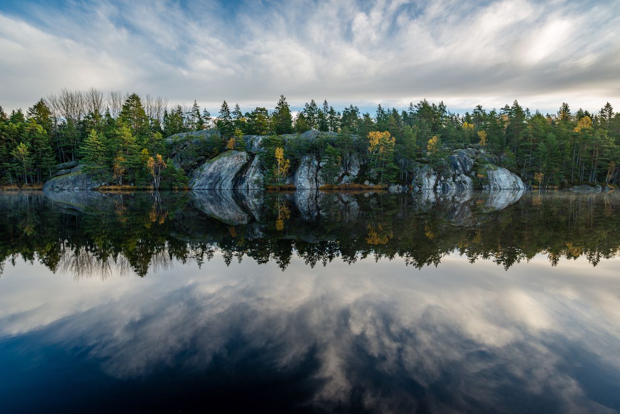 Forest-and-cliffs-mirrored-in-calm-lake Forest-and-cliffs-mirrored-in-calm-lake